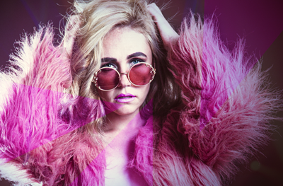 A beautiful white blonde woman wearing a pink fur coat and a pair of sunglasses